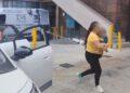 Fotografía de una mujer sosteniendo a un bebé entre brazos caminando hacia la puerta del hospital mientras a su lado hay un automovil estacionado con las puertas abiertas y una ambulancia a la esquina del edificio que se alcanza a notar como fondo